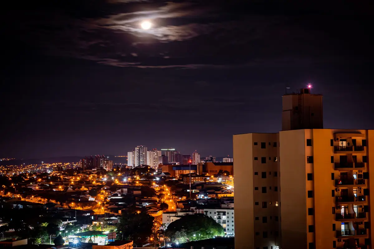 Campinas seen from above at night, with the city lit up under a full moon